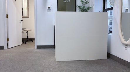 Reception area at Bymilauryss, New Brunswick, New Jersey, US, featuring minimalist decor and greenery.