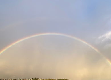 A vibrant rainbow arcs over Porirua, near Beach Bliss Massage, Wellington Region, NZ, creating a serene backdrop.