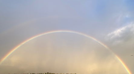 A vibrant rainbow arcs over Porirua, near Beach Bliss Massage, Wellington Region, NZ, creating a serene backdrop.