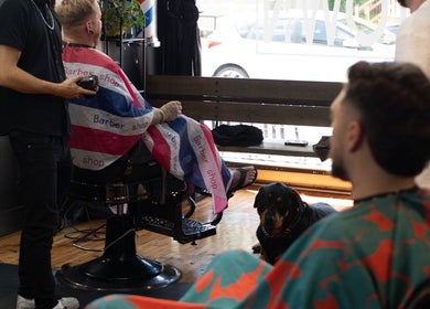 Barber working on a client at Motown Granby, Granby, Quebec, CA with a dog nearby.