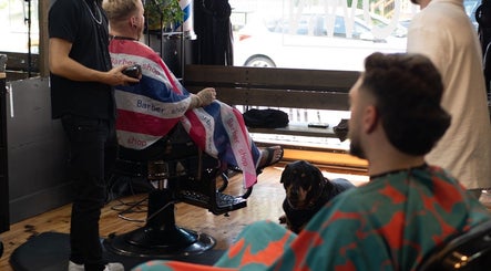 Men receiving stylish haircuts at Motown Granby in Granby, Quebec, CA, with a calm dog nearby.