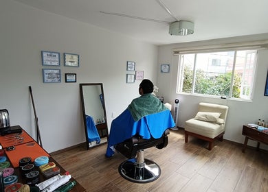 Sala de belleza en Home Harmony, Ciudad De México. Un cliente sentado en una silla con toalla verde.