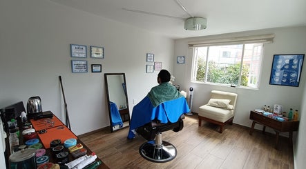 Sala de belleza en Home Harmony, Ciudad De México. Un cliente sentado en una silla con toalla verde.