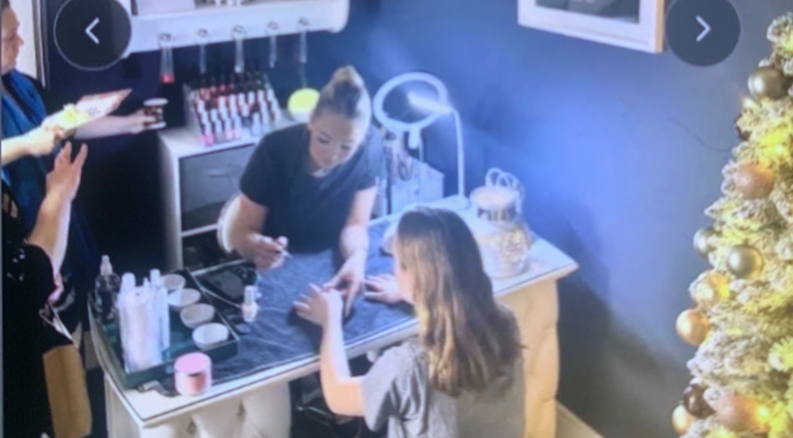 Nail technician painting nails at Beauty by Scarlett, Hastings, England, GB with colorful polish display.