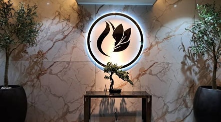 Elegant entry at Lindo Clinic, Kuala Lumpur featuring illuminated logo and potted plants.