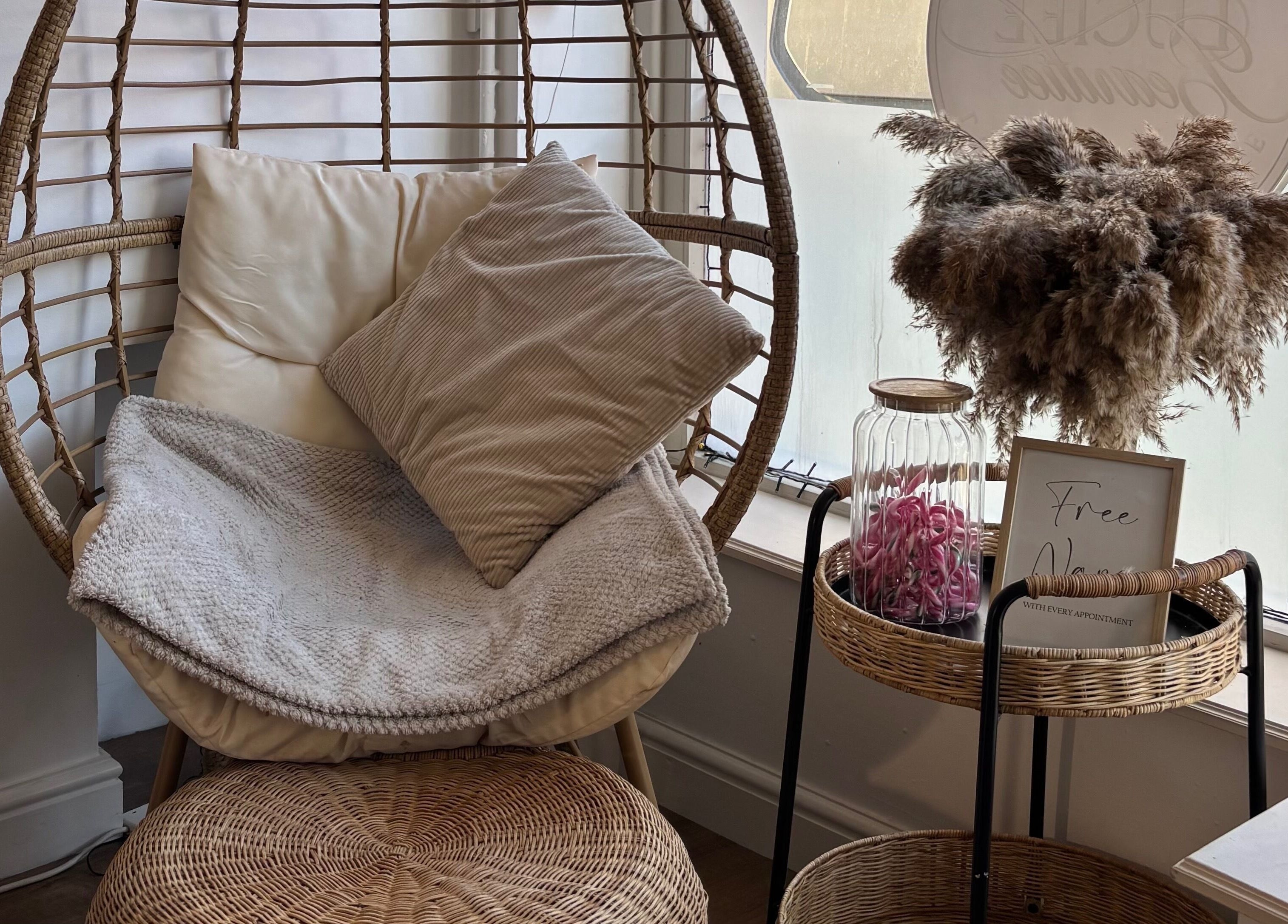 Relaxing wicker chair nook at KB Beauty Room, Senghenydd, Wales, GB, offering a tranquil spa ambience.