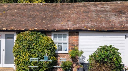 Exterior view of Zoë-Erika Massage and Reiki in Haywards Heath, England, GB, showcasing lush plants and rustic charm.