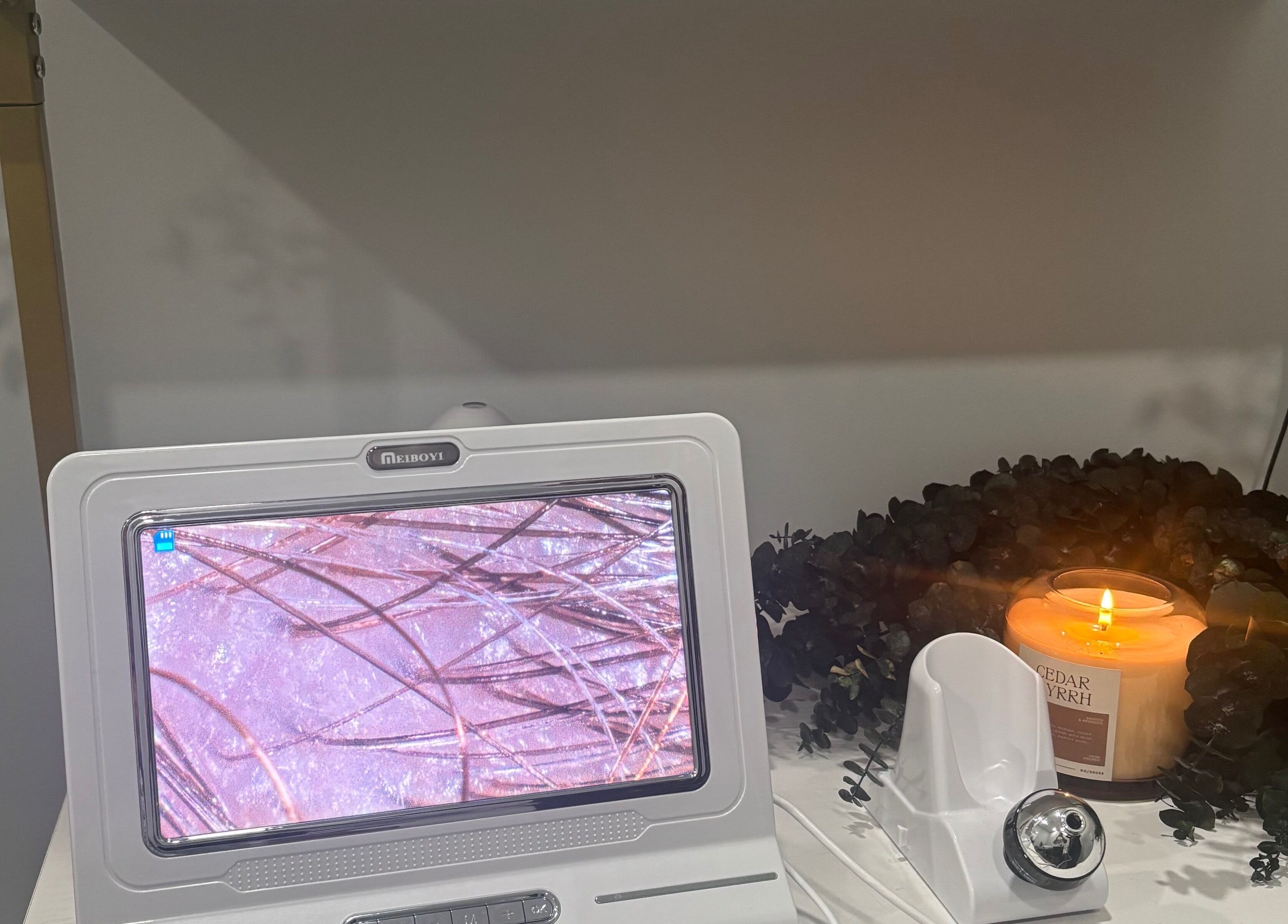 Relaxing setup at Bright & Blissful, Brunswick, Georgia, US with a candle, foliage, and skincare monitor.