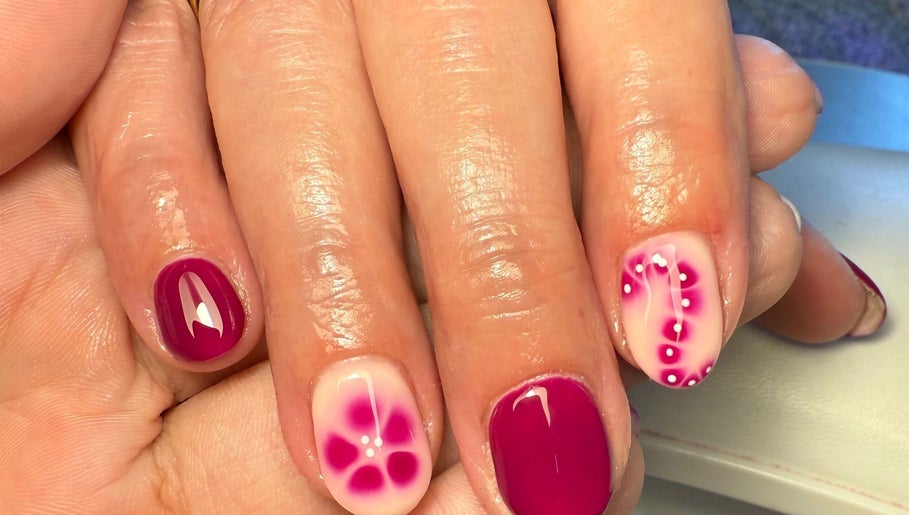 Elegant floral nail art at Daisie Mae Beauty, Lechlade, England, GB. Vibrant pink and white manicure design.