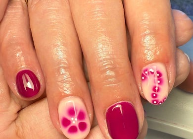 Elegant floral nail art at Daisie Mae Beauty, Lechlade, England, GB. Vibrant pink and white manicure design.