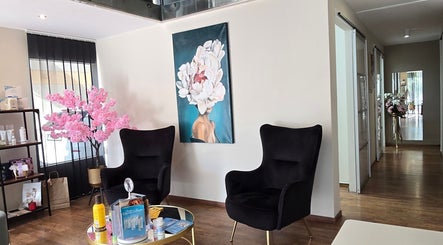 Σαλόνι Mandarinlaser_aesthetics στη Λεμεσό με μαύρες πολυθρόνες και ροζ δέντρο διακοσμητικό.