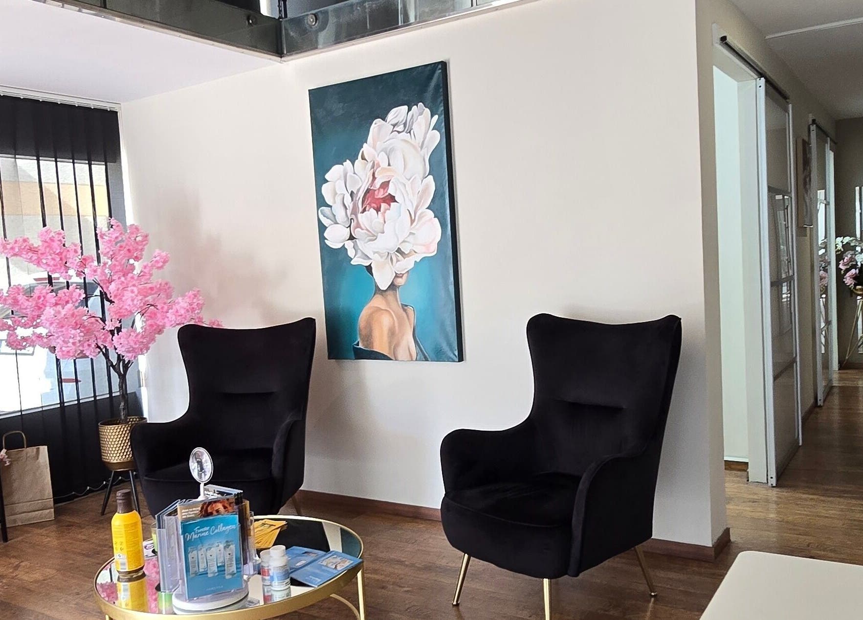Άνετος χώρος υποδοχής στο Mandarinlaser_aesthetics, Λεμεσός, με ανθισμένη διακόσμηση και μαύρες πολυθρόνες.