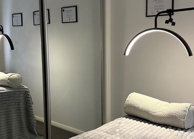 Tranquil treatment room at Latenight_brows, Airds, New South Wales, AU with a plush bed and modern lighting.