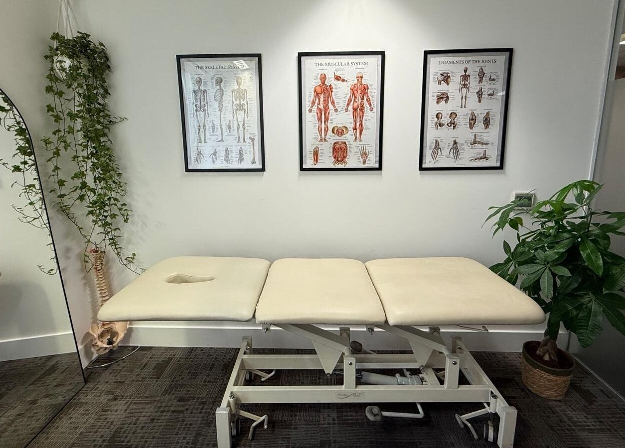 Therapy room at The Body Formulae in London, England, GB with massage table, anatomical charts, and plants.
