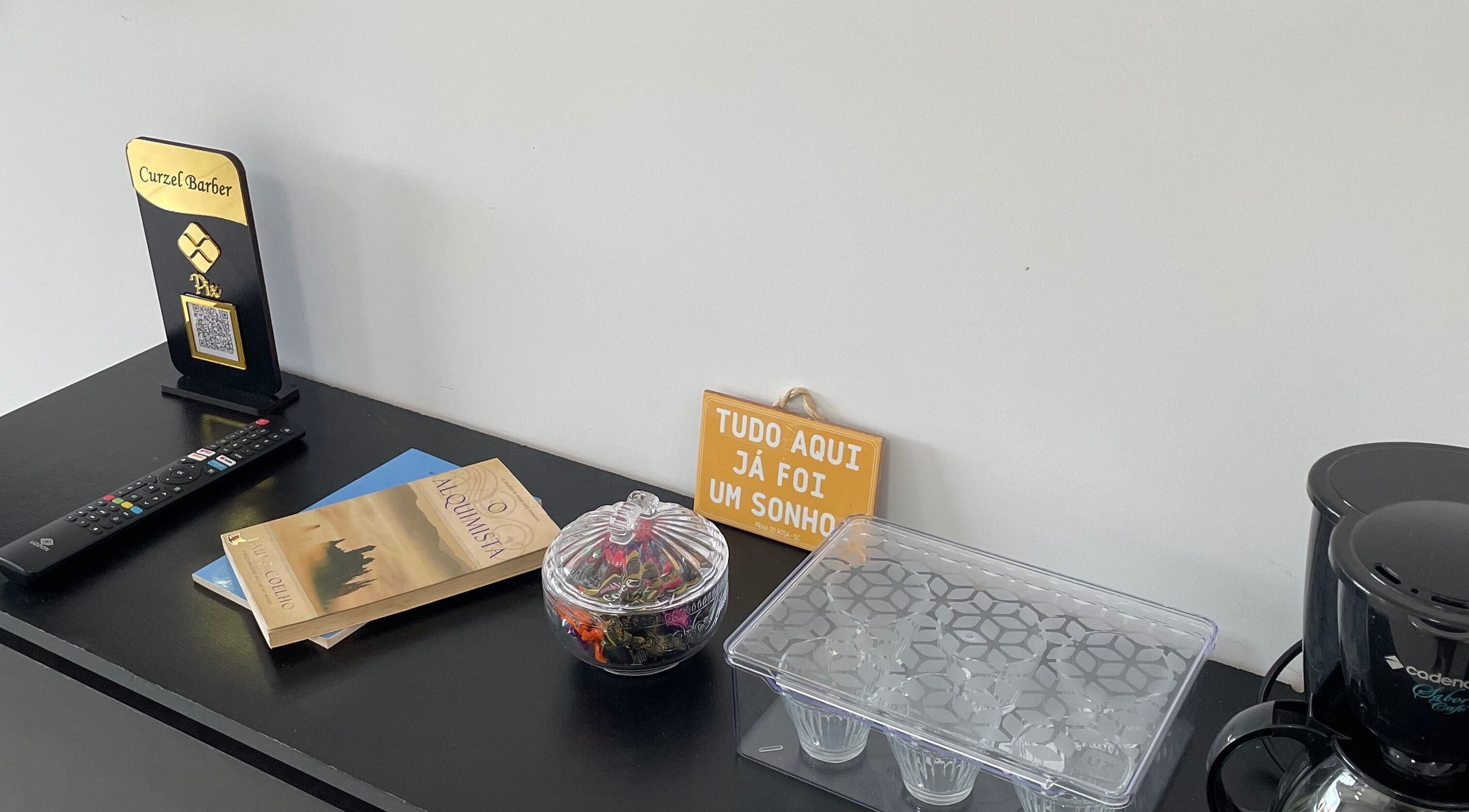 Decoração acolhedora no LurczBarber, Rio Grande Do Sul, BR com livros, placa motivacional e cafeteira.