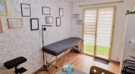 Salle de soins lumineuse de Dermo Perfect à Prunay-en-Yvelines, Île-de-France, FR, avec table et diplômes.