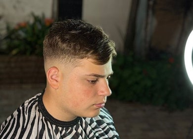 Side profile of a young man with a fresh fade haircut at Delpa Barber, Arroyo Seco, Santa Fe, AR, under soft light.