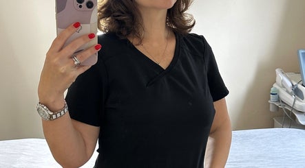 A woman taking a mirror selfie at The Skinbar, Атлон, Уэстмит, IE, showcasing a stylish black outfit.