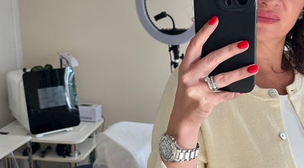 Woman with red nails taking a selfie at The Skinbar, Атлон, Уэстмит, IE, reflecting salon ambience.