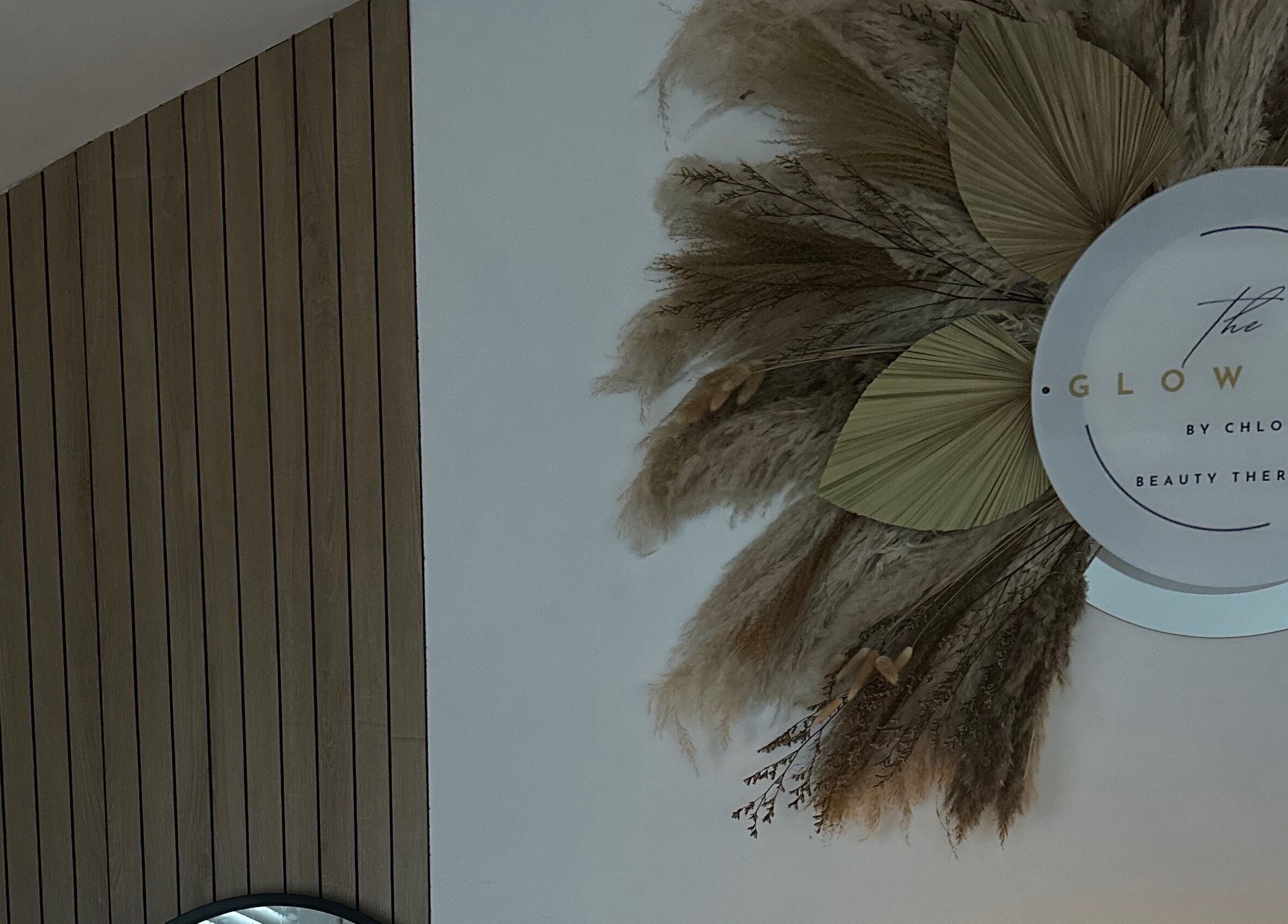 The Glow Hut logo with decorative foliage on wooden panel wall in Avon Dassett, England, GB.