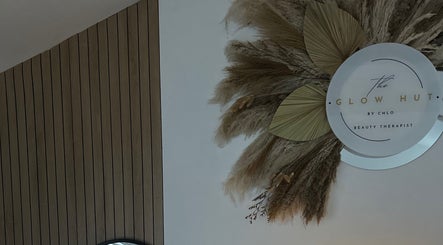 The Glow Hut logo with decorative foliage on wooden panel wall in Avon Dassett, England, GB.