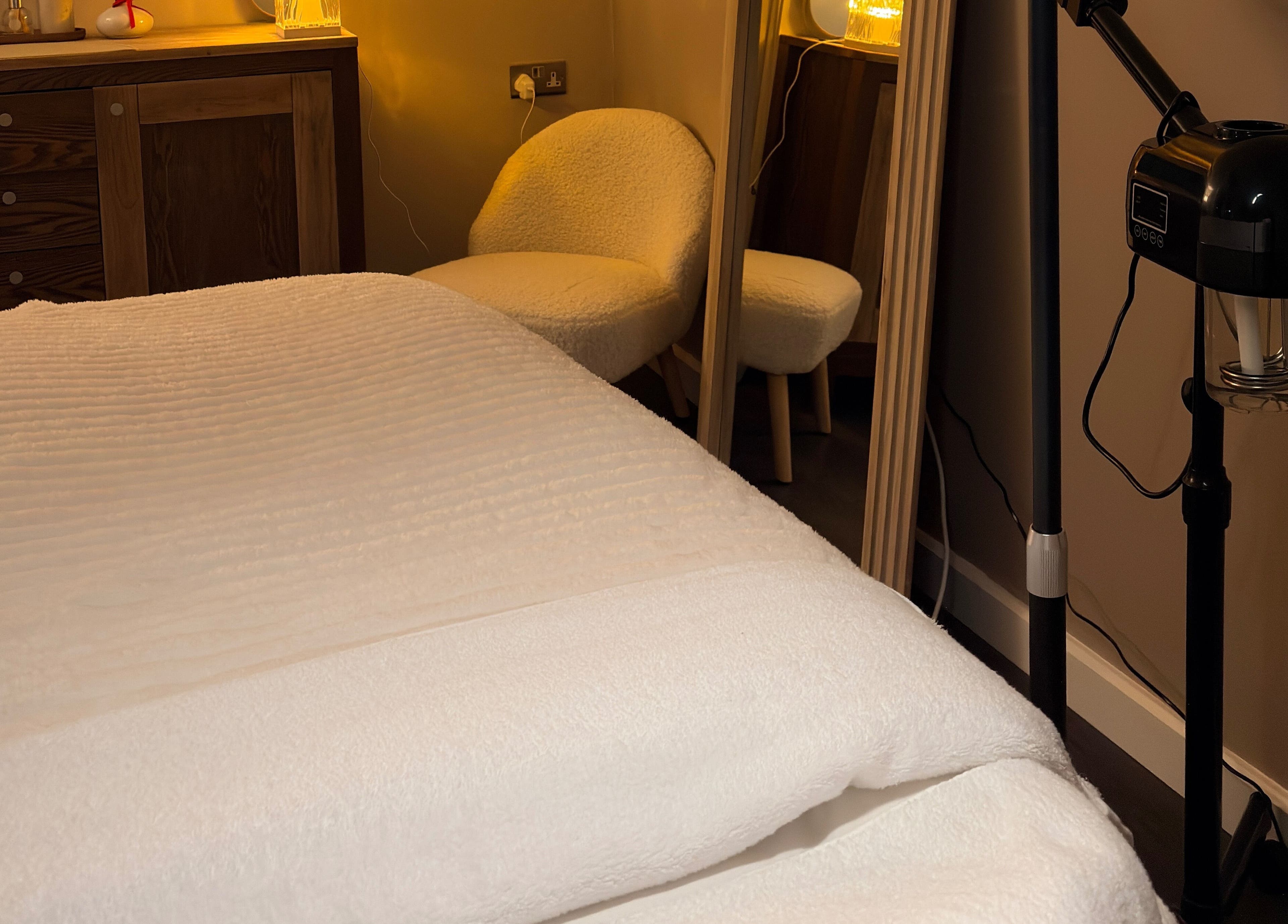 Glow Beauty by Sian treatment room in Solihull, England features a cozy massage table with ambient lighting.
