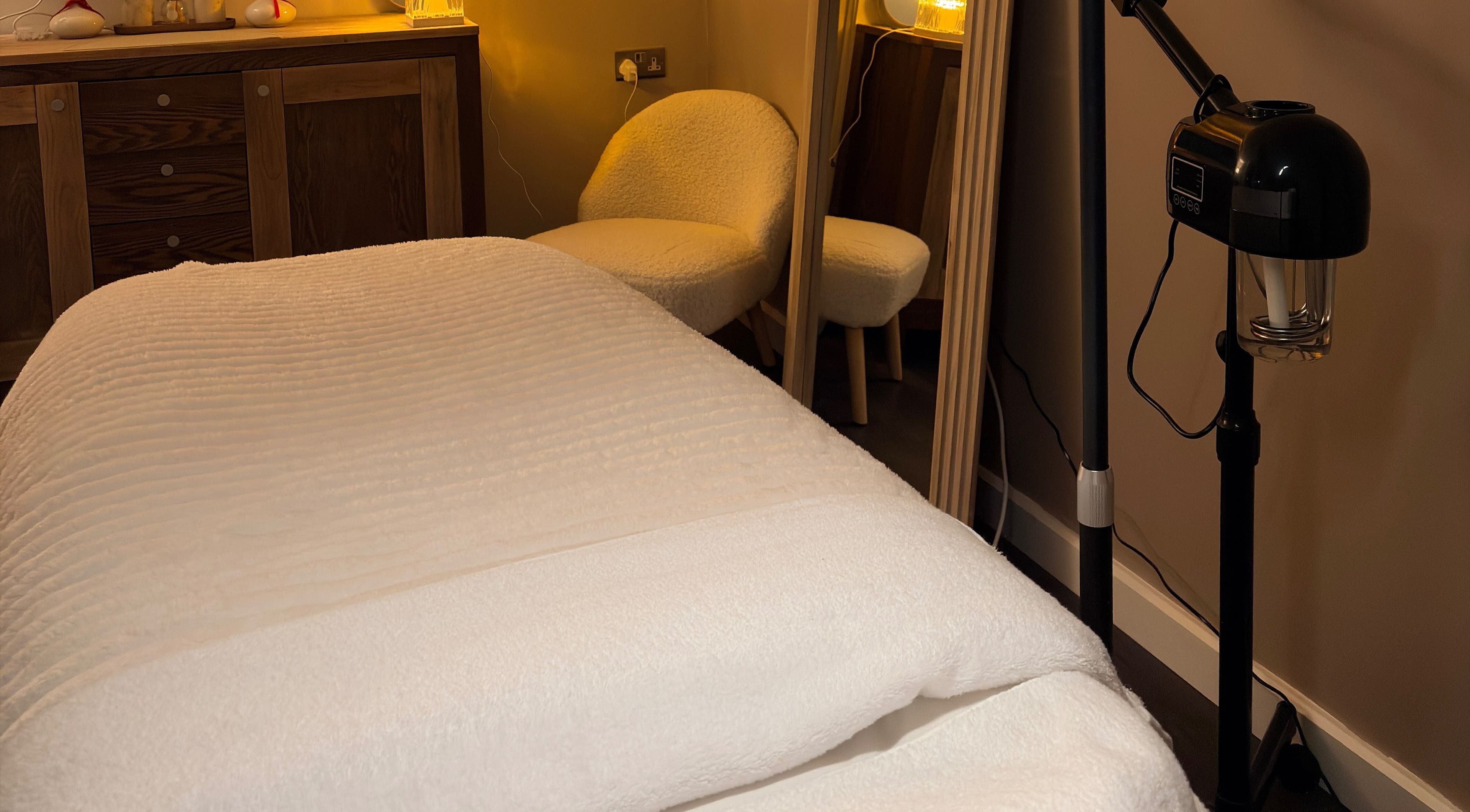 Glow Beauty by Sian treatment room in Solihull, England features a cozy massage table with ambient lighting.