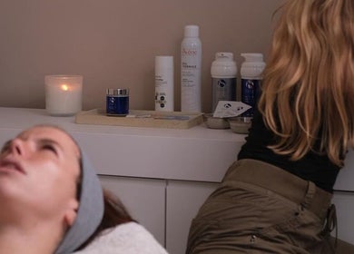 Client receiving facial treatment at Alma Aesthetics, Brighton And Hove, England, GB. Candles and products in view.