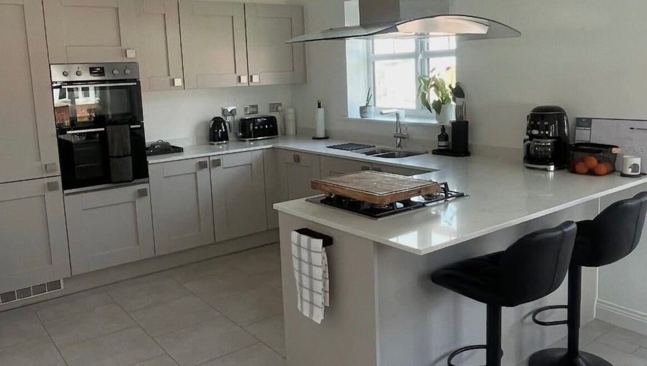 Modern kitchen at Maid For It, Widnes, England, GB showcasing sleek countertops and black bar stools.
