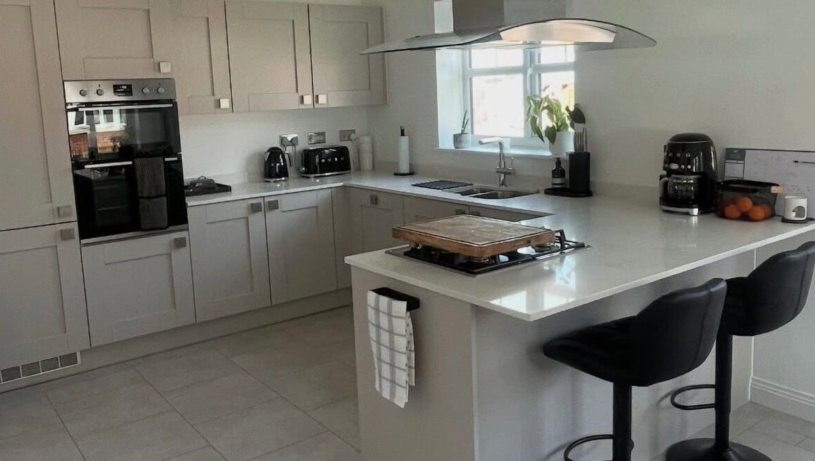 Modern kitchen at Maid For It, Widnes, England, GB showcasing sleek countertops and black bar stools.