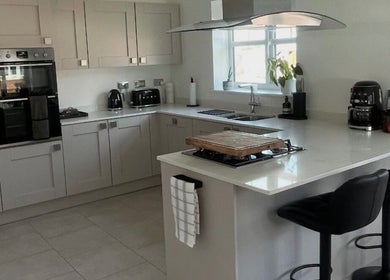 Modern kitchen at Maid For It, Widnes, England, GB showcasing sleek countertops and black bar stools.