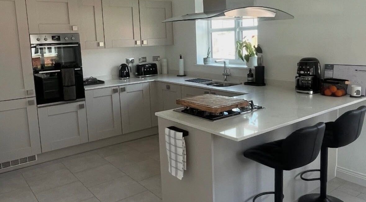 Modern kitchen at Maid For It, Widnes, England, GB showcasing sleek countertops and black bar stools.