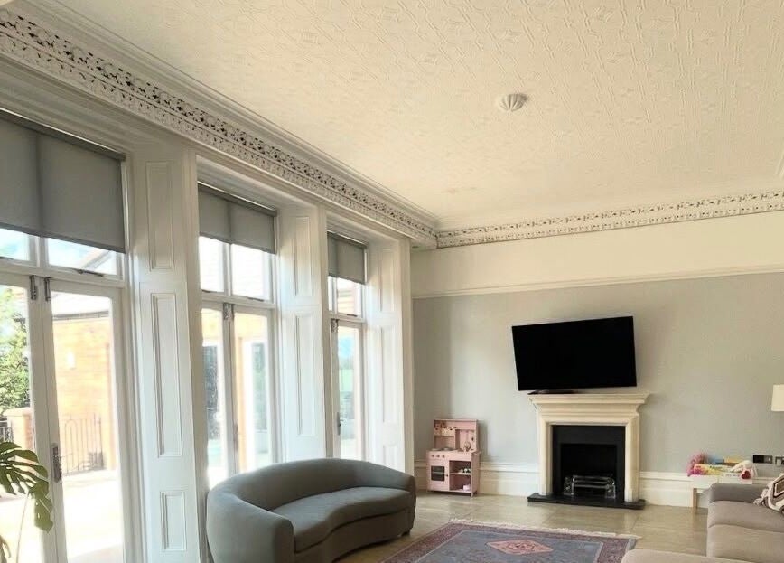 Sunlit elegant lounge at Maid For It, Widnes, England, GB with plush sofas and decorative fireplace.