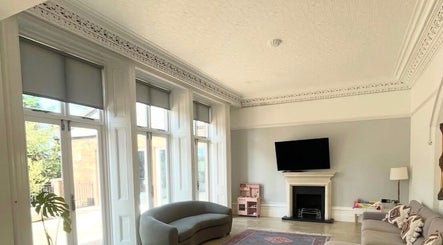 Sunlit elegant lounge at Maid For It, Widnes, England, GB with plush sofas and decorative fireplace.