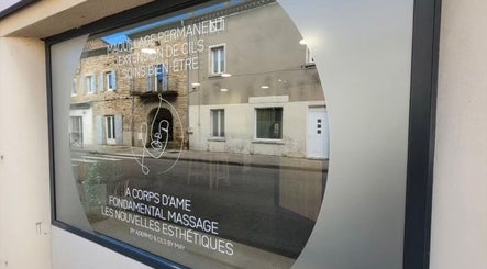 Vitrine de Fondamental Massage à Saint-Privat, Auvergne-rhône-alpes, FR, reflétant un bâtiment en face.