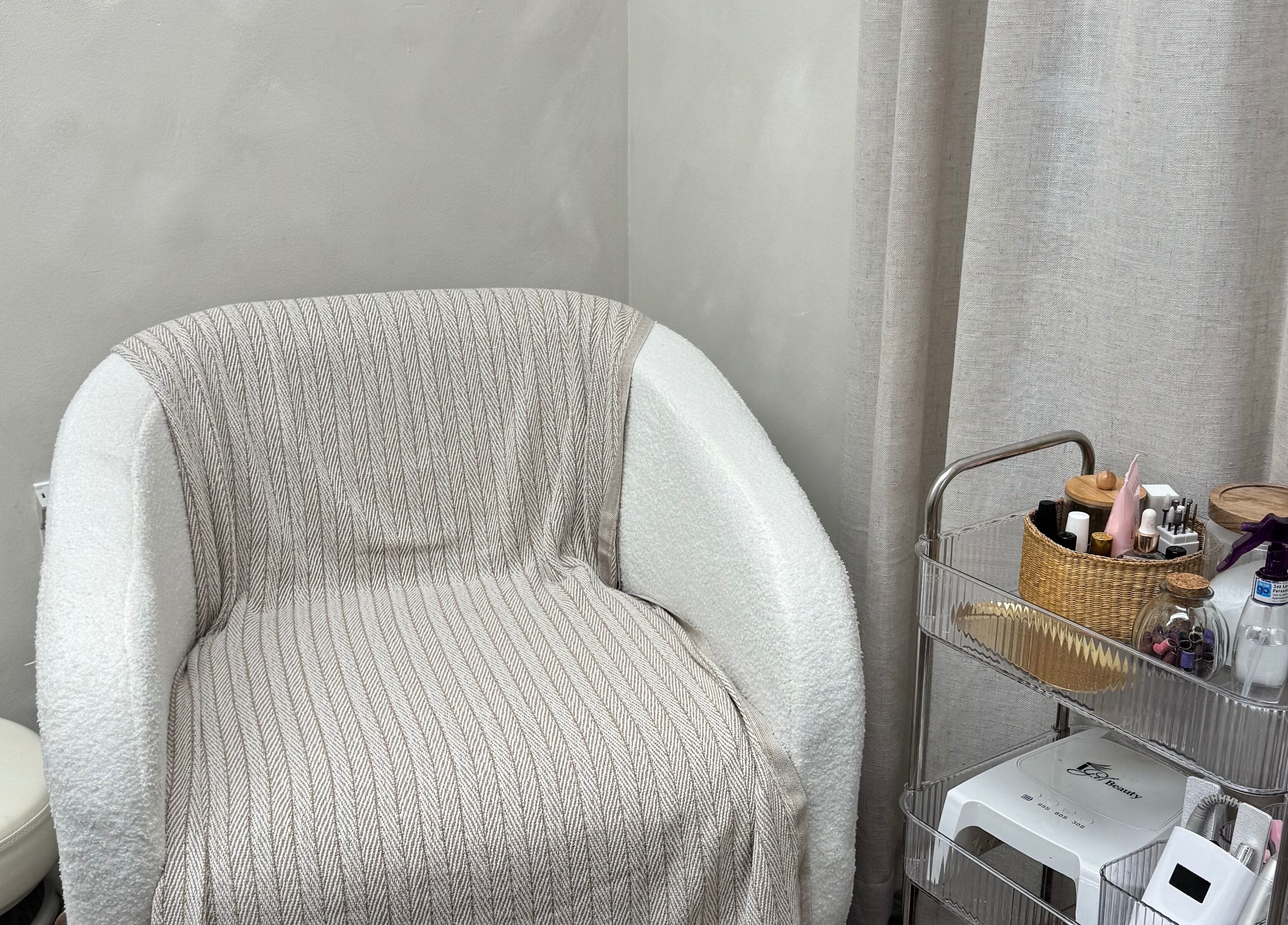 Espacio acogedor en AMAR Nails Studio, Miami, Florida, US con silla y carrito de belleza.