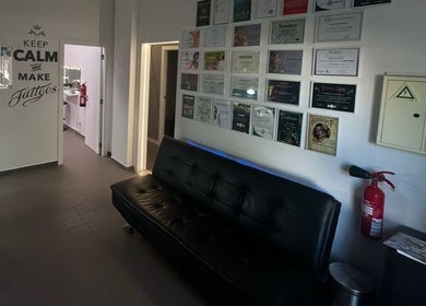 Interior do Sorry Mom Studio em Fátima, Santarém, PT, com sofá preto e parede de certificados.