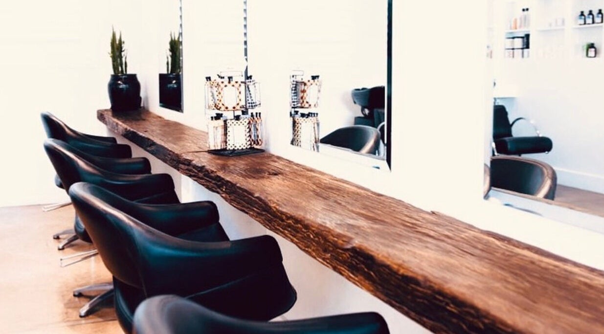 Sleek salon chairs and rustic counter at Mana Hair, Avalon Beach, NSW, AU, offering a cozy beauty experience.