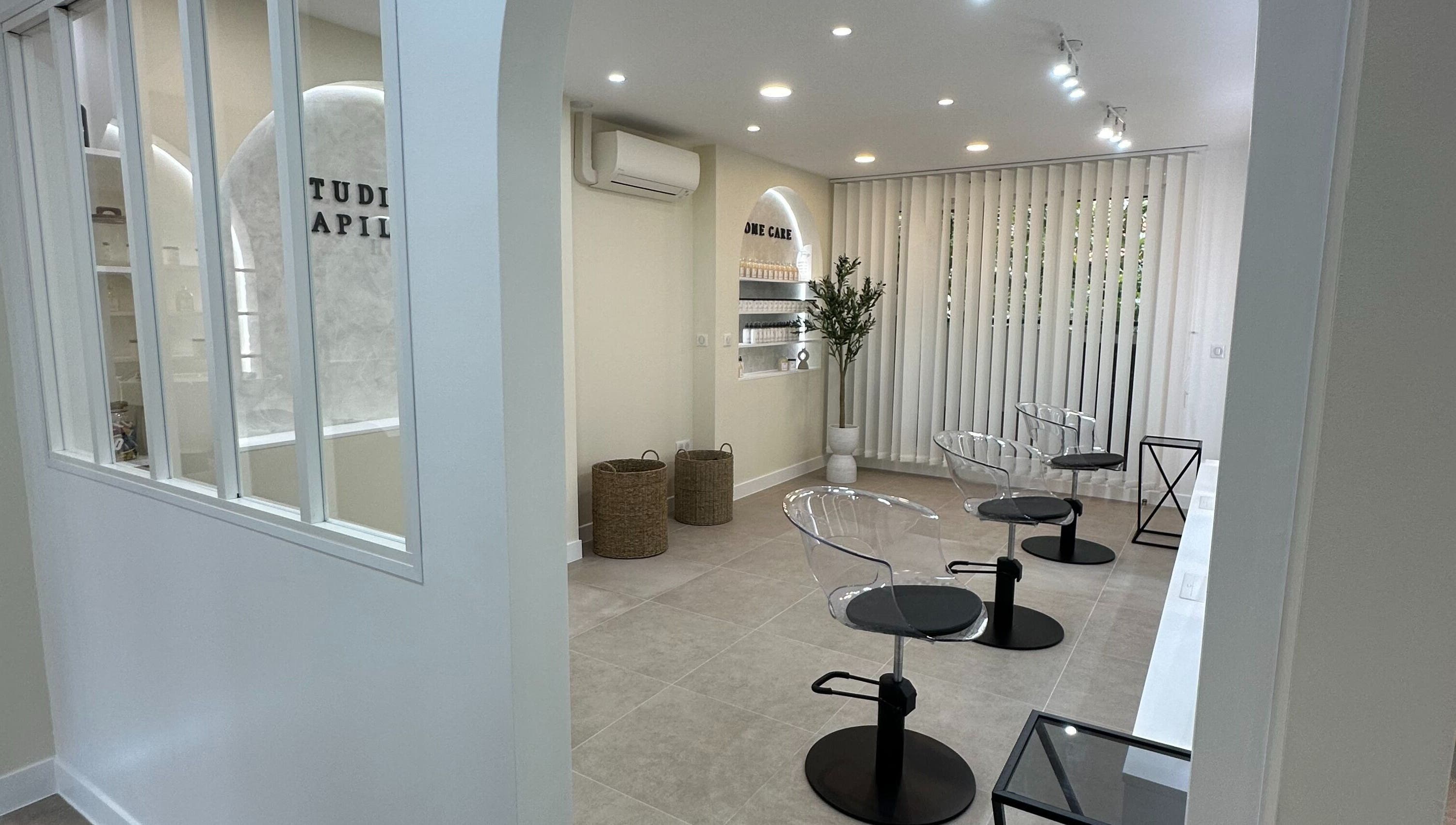 Intérieur moderne de STUDIO CAPILLAIRE à Suresnes, Île-de-France, FR avec sièges transparents et déco minimaliste.