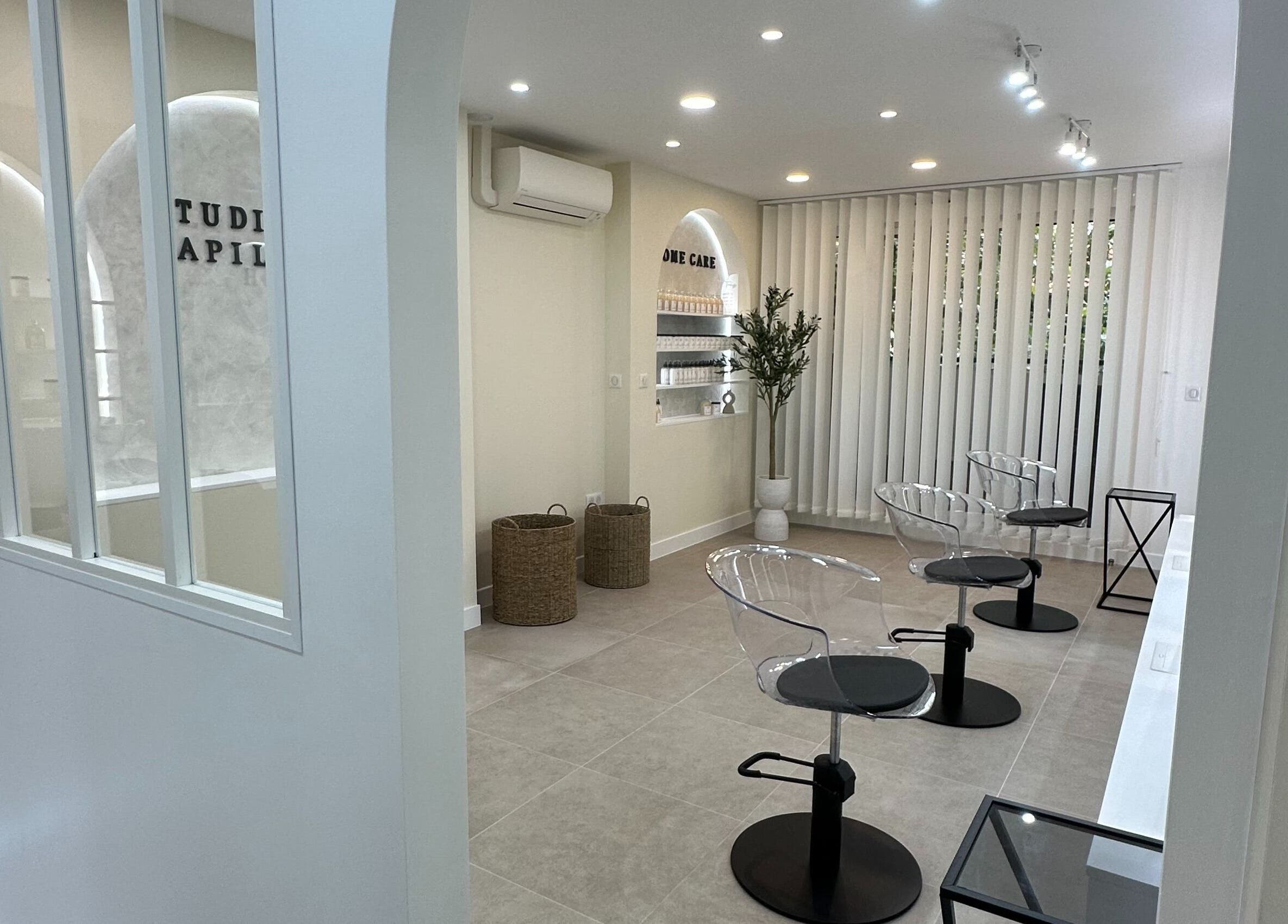 Intérieur moderne de STUDIO CAPILLAIRE à Suresnes, Île-de-France, FR avec sièges transparents et déco minimaliste.