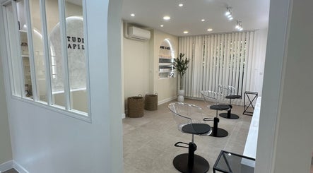 Intérieur moderne de STUDIO CAPILLAIRE à Suresnes, Île-de-France, FR avec sièges transparents et déco minimaliste.