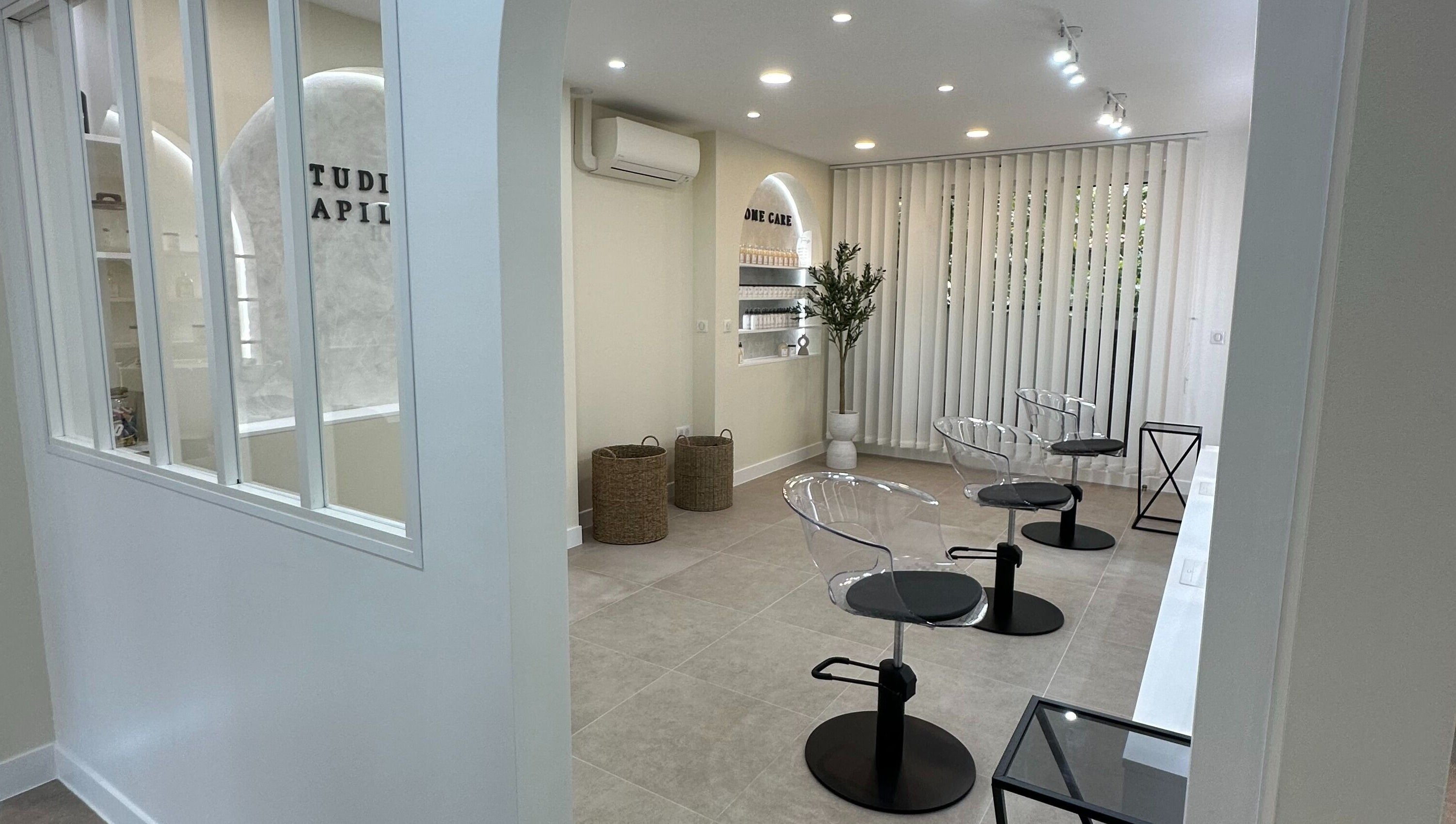 Intérieur moderne de STUDIO CAPILLAIRE à Suresnes, Île-de-France, FR avec sièges élégants et déco minimaliste.