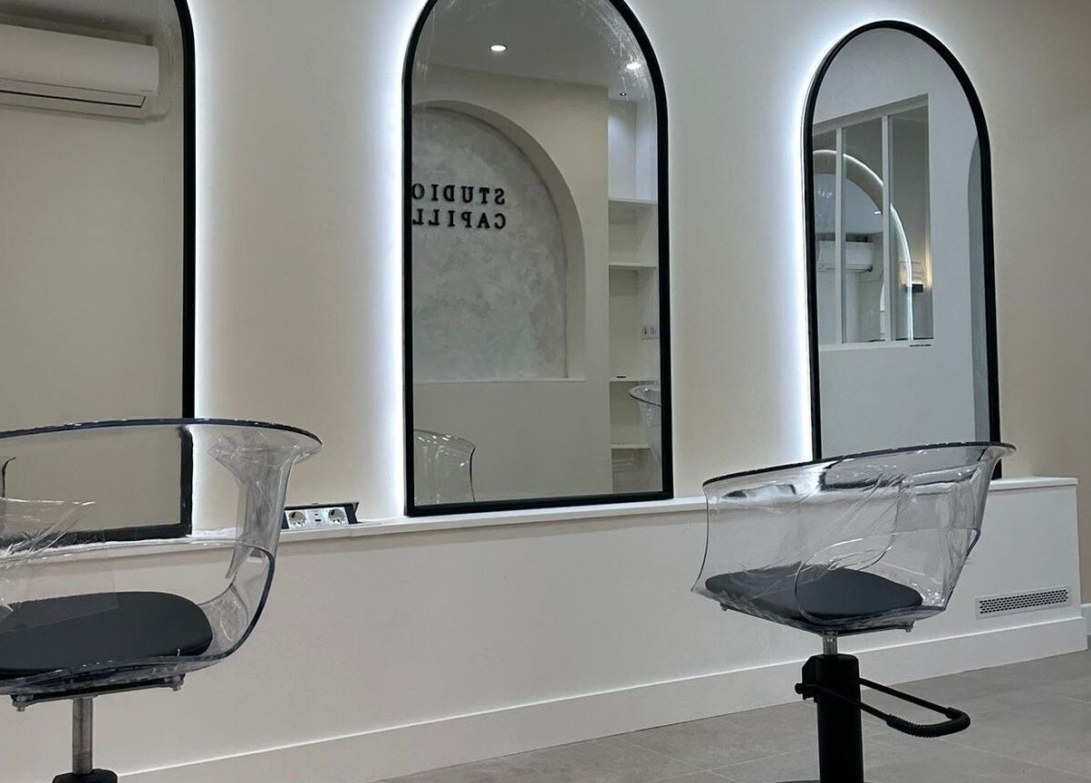 Salon moderne STUDIO CAPILLAIRE à Suresnes, Île-de-France, avec sièges transparents et grands miroirs.