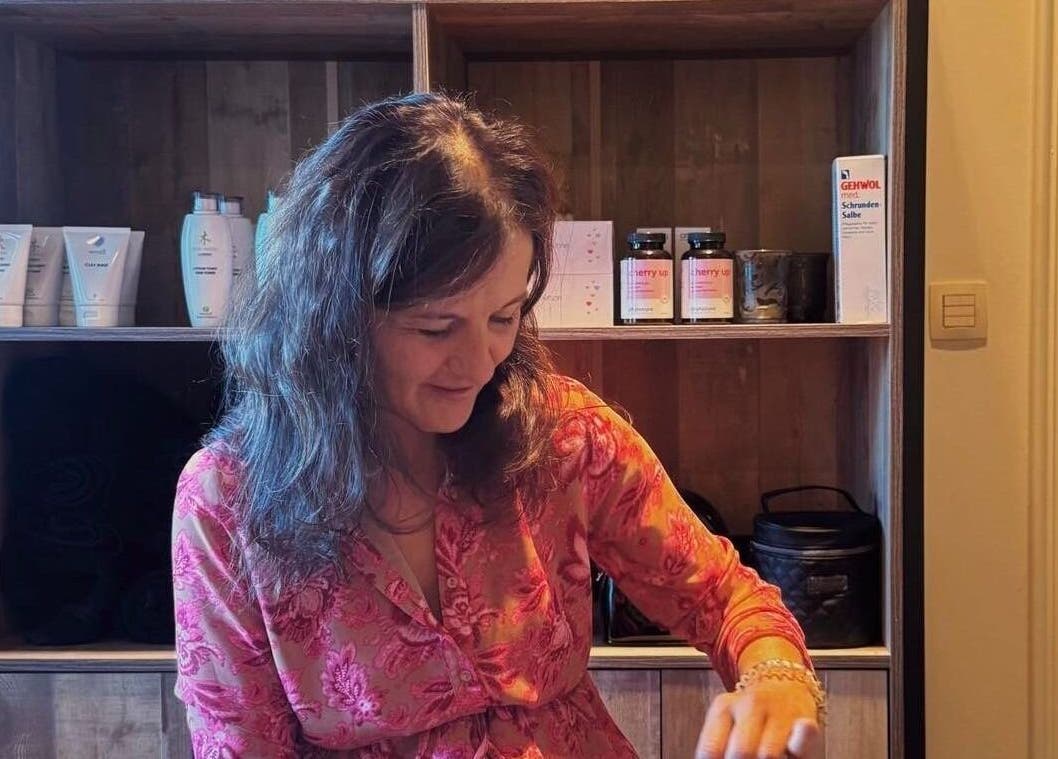 Vrouw in Schoonheidsinstituut Amaris, Izegem, Vlaanderen, BE, verzorgt klant met producten op achtergrond.