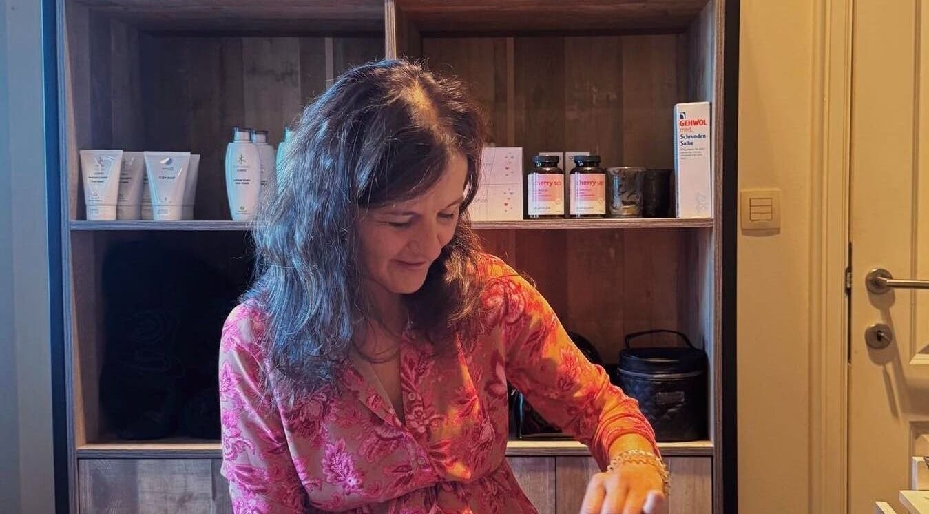 Vrouw in Schoonheidsinstituut Amaris, Izegem, Vlaanderen, BE, verzorgt klant met producten op achtergrond.