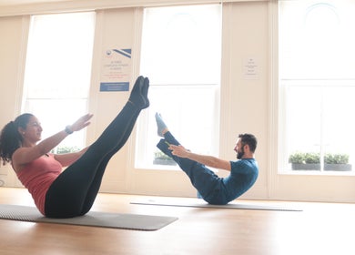 Two people practicing Pilates at The Peak Wellness Studio, Dublin, County Dublin, IE in a sunlit room.
