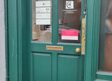 Green door entrance of The Peak Wellness Studio in Dublin, County Dublin, IE with signs visible.