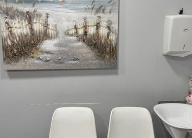 Simplybrite washroom in Northwood, England, featuring serene decor with chairs, sink, and beach-themed art.