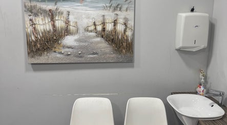 Simplybrite washroom in Northwood, England, featuring serene decor with chairs, sink, and beach-themed art.