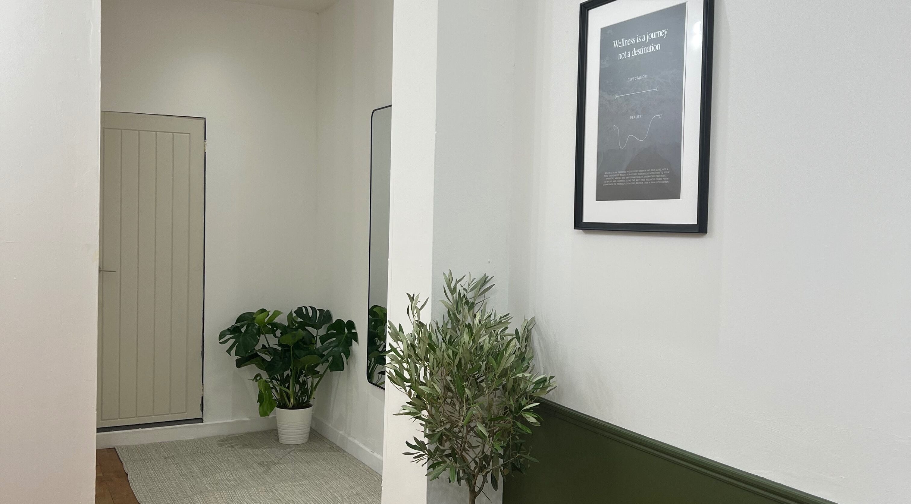 Serene hallway at Nour Wellness in Stirling, Scotland, with plants and inspirational art.